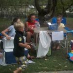 Kids sitting down in the shade to take a break from the sun at the annual picnic